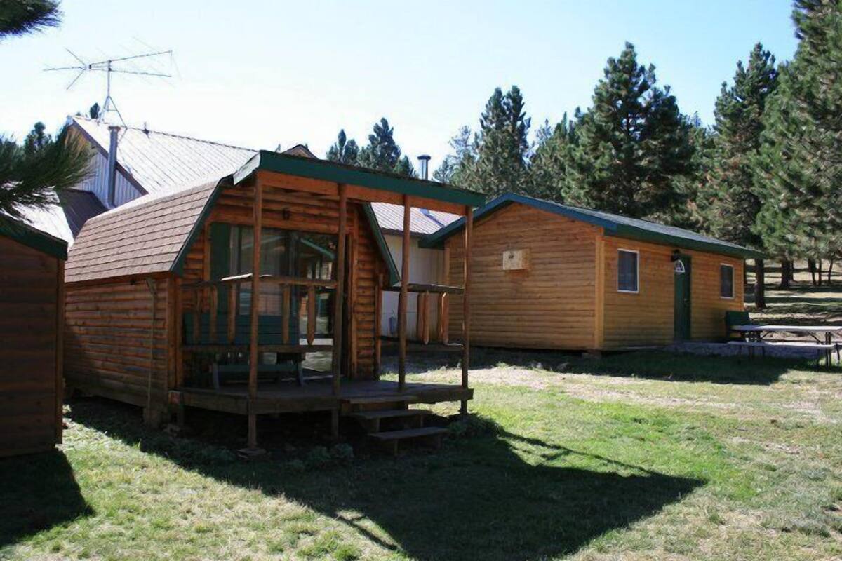 A rustic cabin with a porch, a small deck, and a picnic table.