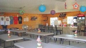 A diner with wooden walls, tables with American flags, and a Coca-Cola refrigerator. - Rush No More RV Resort and Cabins - Campground (Sturgis)