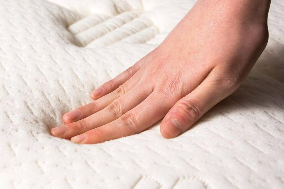 A hand resting on a textured white surface, likely a bed or couch.