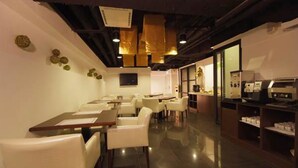 A restaurant with white chairs, a long counter, and a television. - Lio Hotel (Taipei)