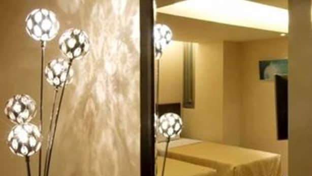 A hotel room with a large mirror reflecting a bed and a wall-mounted lamp with spherical lights. - Lio Hotel (Taipei)