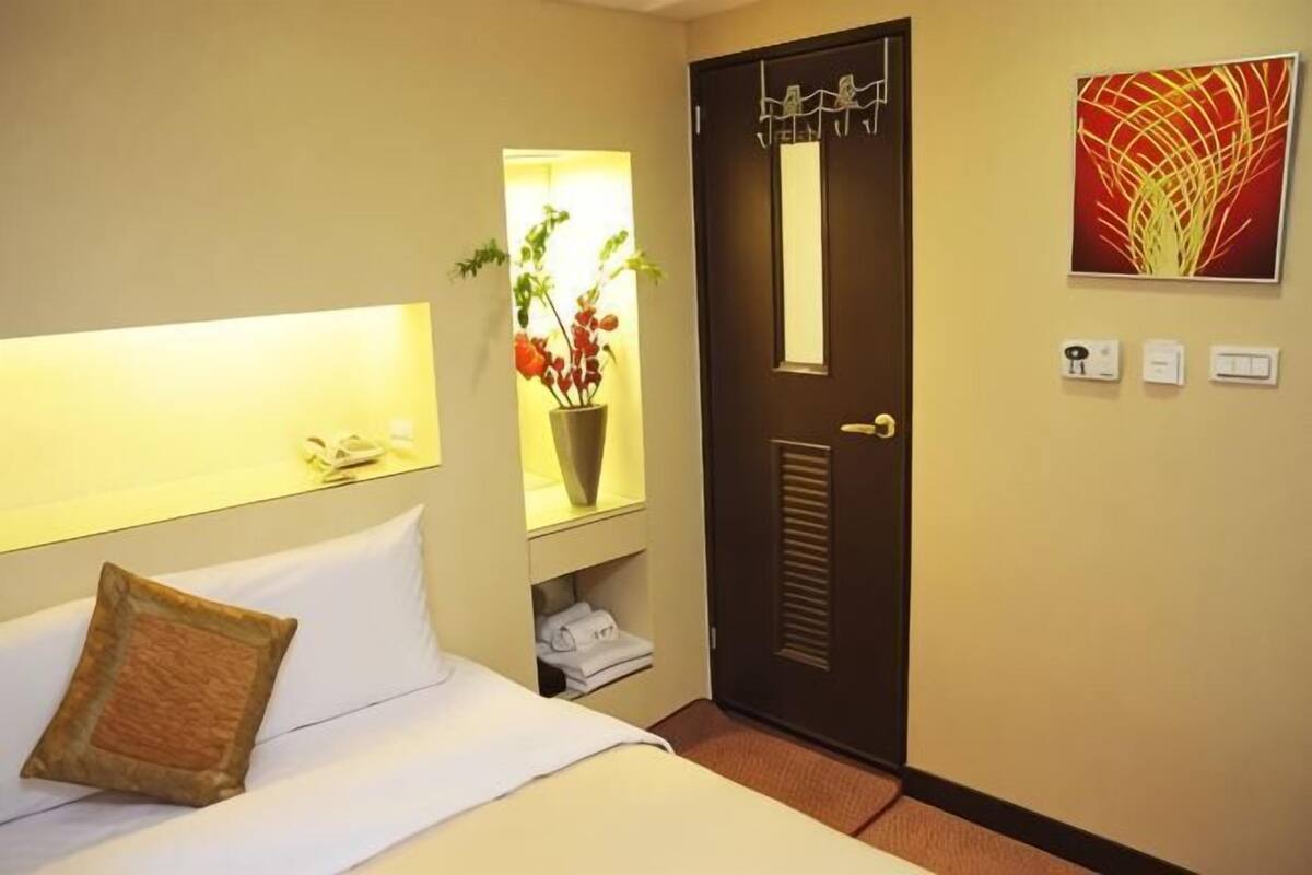 Une chambre d’hôtel comprenant un lit, une table de chevet, un miroir, une porte et une œuvre d’art accrochée au mur.