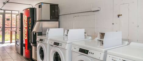 A laundry area with four washers and dryers, a vending machine, and a large air vent.