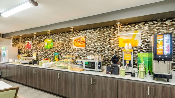 A self-service breakfast station with various food options, a microwave, and a waffle maker. - Quality Inn Bristol Pinnacle Area (Bristol)