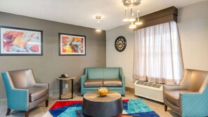 A modern living room with a teal sofa, two leather armchairs, a round coffee table, and colorful rugs. - Quality Inn Bristol Pinnacle Area (Bristol)