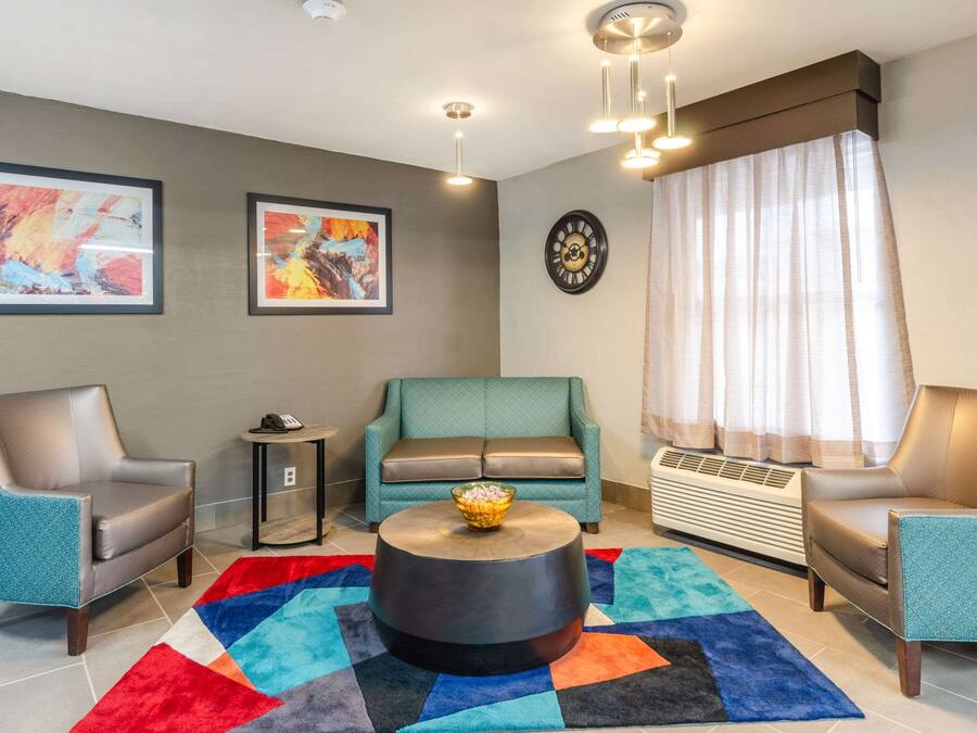 Una sala de estar moderna con un sofá azul turquesa, dos sillones de cuero, una mesa de centro redonda y alfombras coloridas.