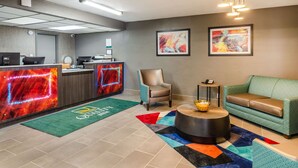 A hotel lobby with a reception desk, a green sofa, a chair, and a colorful rug. - Quality Inn Bristol Pinnacle Area (Bristol)