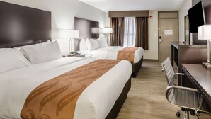 A hotel room with two beds, a desk with a chair, a TV, and a door. - Quality Inn Bristol Pinnacle Area (Bristol)