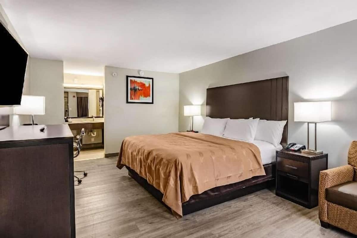 A hotel room with a bed, bedside lamps, a desk, and a chair.