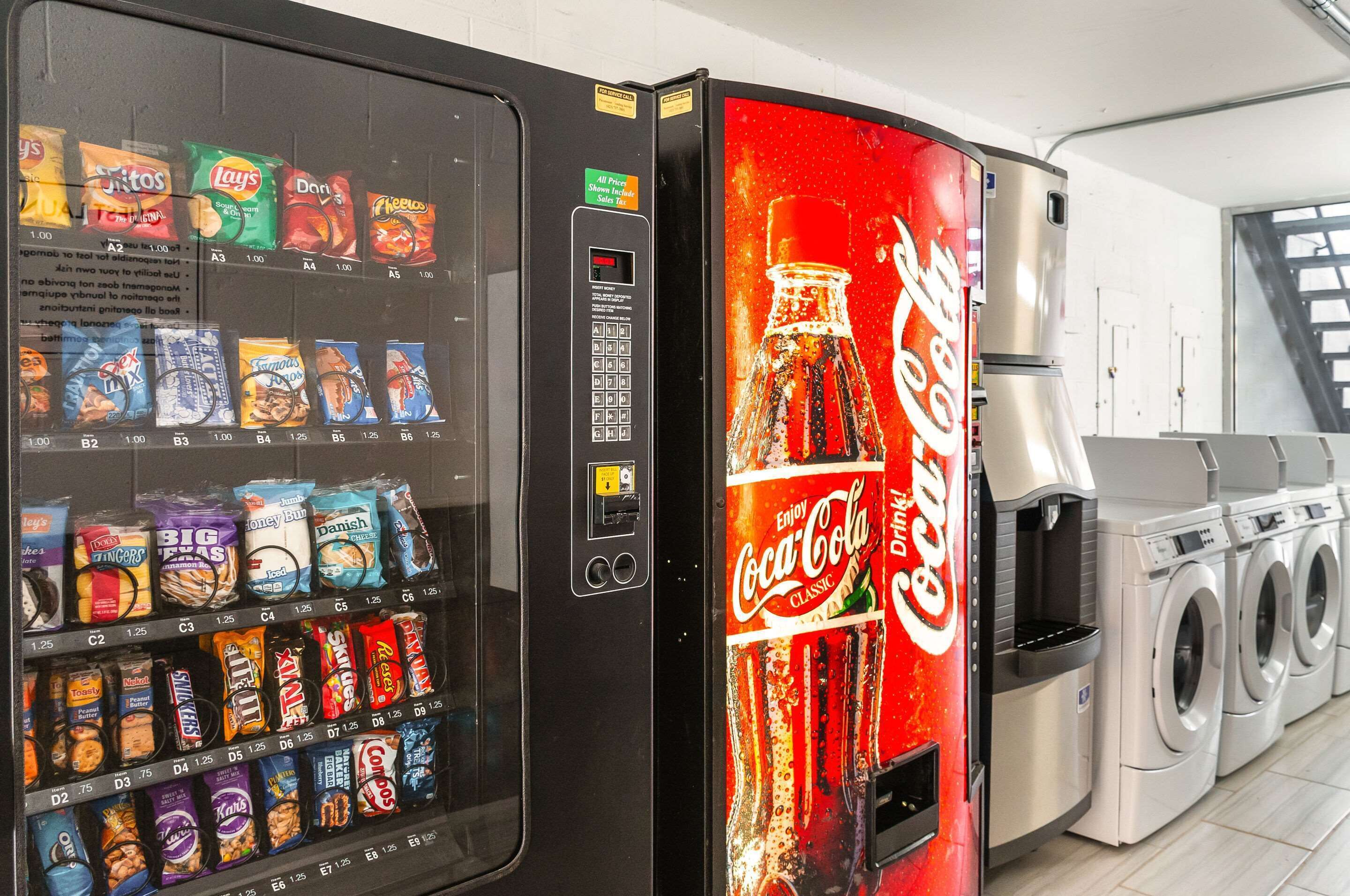 Un distributeur automatique de collations et une machine à Coca-Cola dans une laverie.
