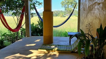 A hammock, a cushioned bench, and a view of a rice field.