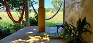 A hammock, a cushioned bench, and a view of a rice field.