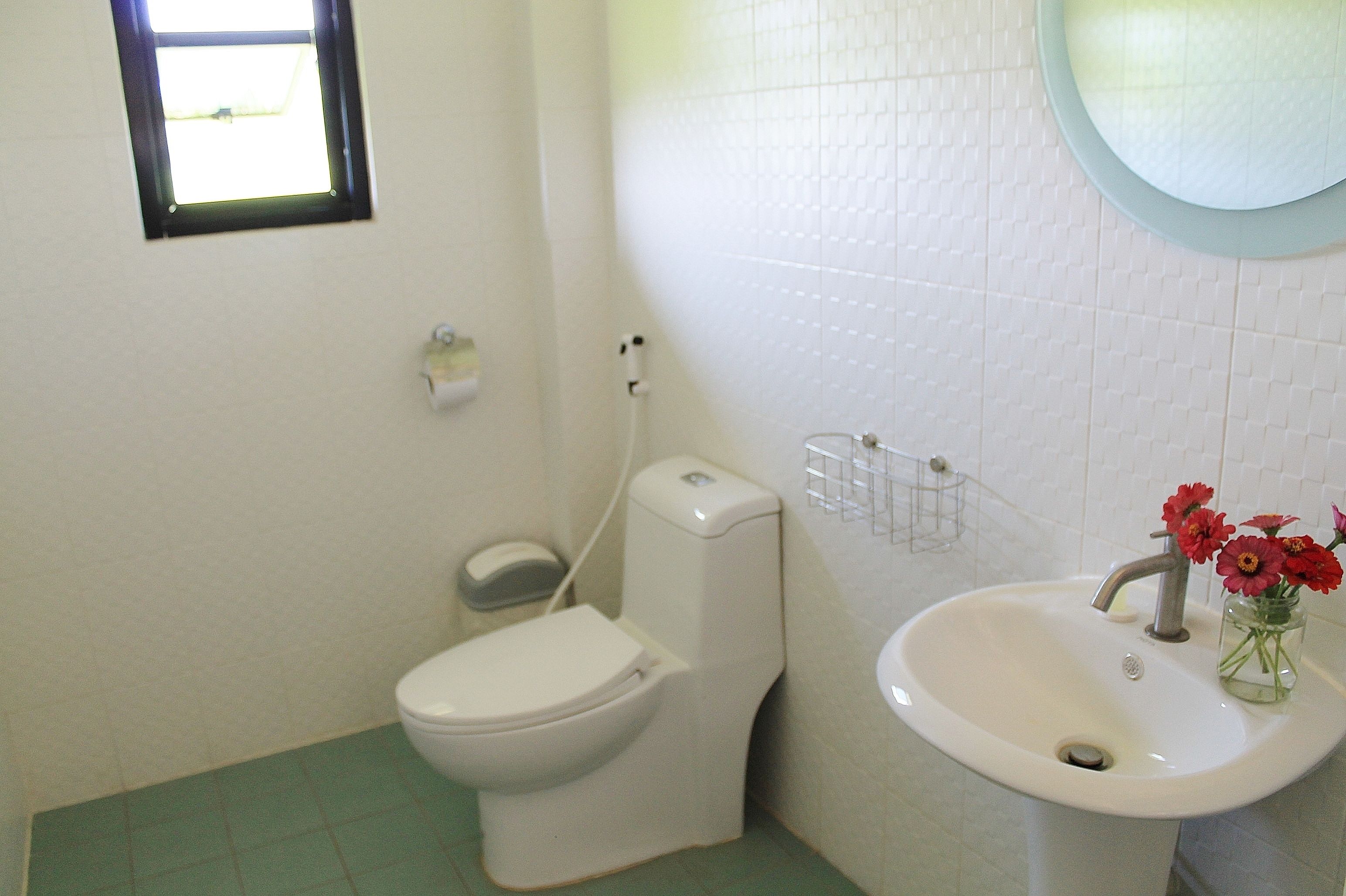 A bathroom with a toilet, sink, and a small window.