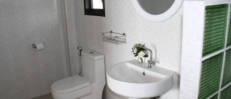 A bathroom with a toilet, sink, and a small window.