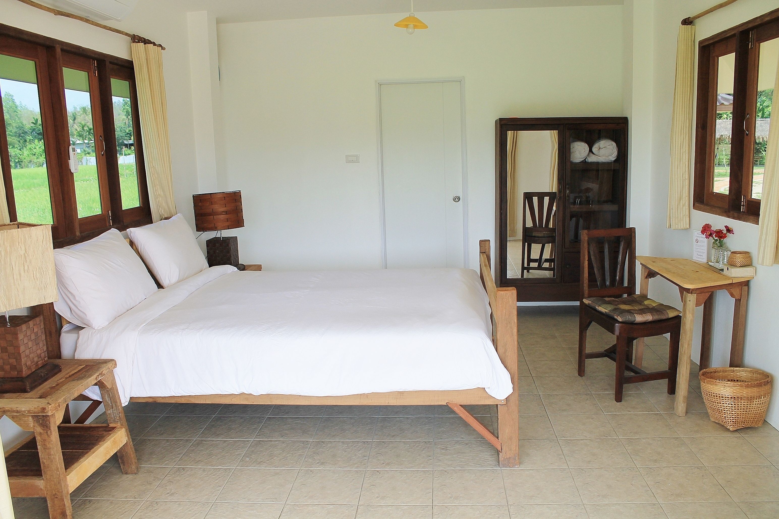 Une chambre à coucher comprenant un lit, des tables de chevet en bois, un bureau, des chaises et une armoire.