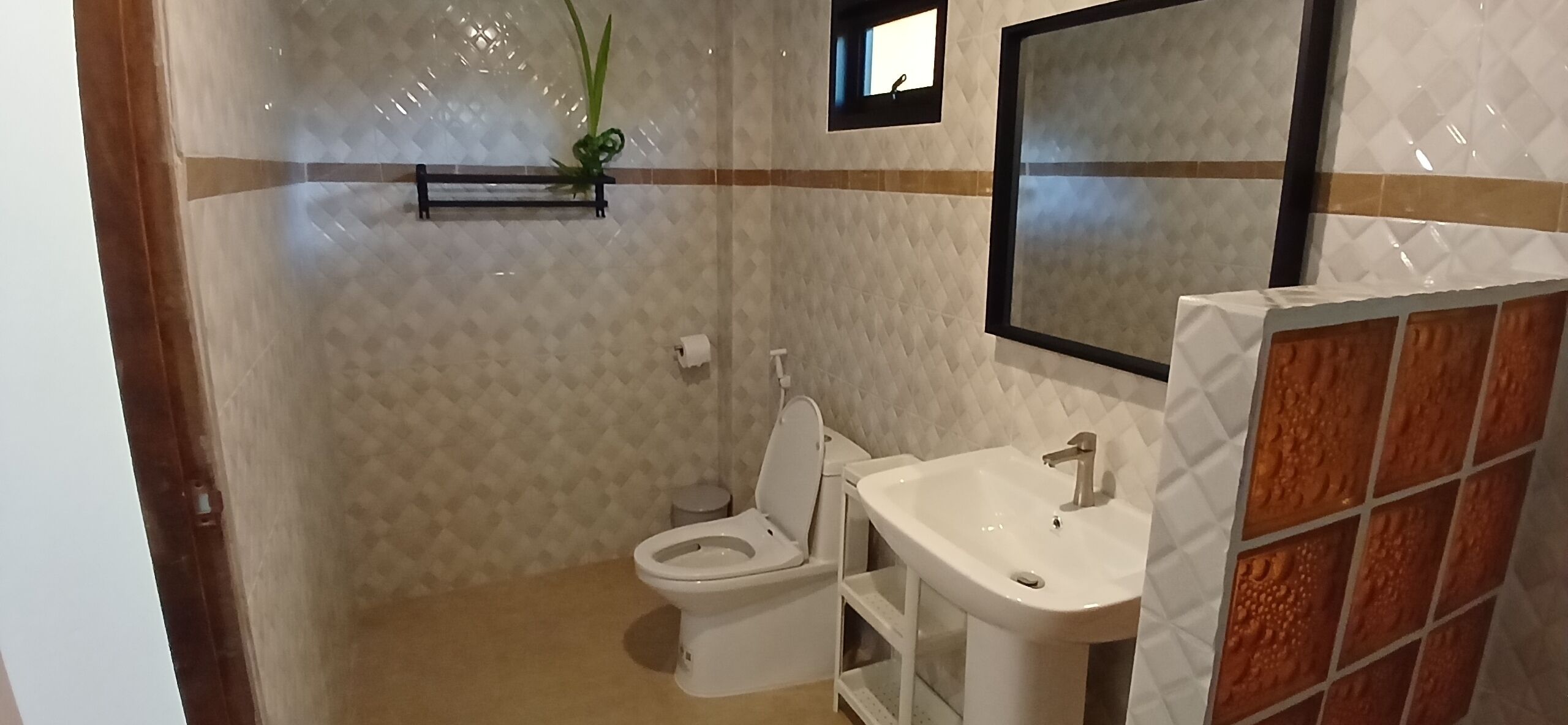 A bathroom with a toilet, sink, and a small mirror.