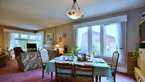 A dining area with a table set for four, surrounded by chairs, a television, and a fireplace. - 10th Avenue Guest House & Suites (Hanover)
