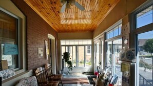 A cozy room with a wooden ceiling, large windows, a seating area with chairs, and a refrigerator with magnets. - 10th Avenue Guest House & Suites (Hanover)