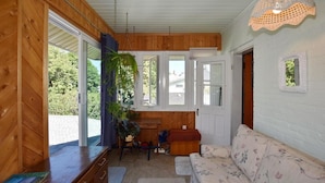 A cozy cabin interior with wooden walls, a sofa, a dining table, and a hanging light fixture. - 10th Avenue Guest House & Suites (Hanover)