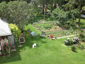 Een verzorgde tuin met een terras, een tafeltje en stoelen.