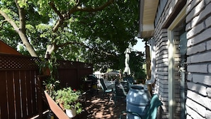 A patio with a wooden deck, outdoor furniture, and a large metal barrel. - 10th Avenue Guest House & Suites (Hanover)