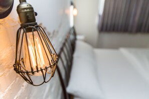 A close-up of a metal-framed light fixture with an exposed filament bulb, attached to a white wall. - Mr Lobster's Secret Den Design Hostel (Taipei)