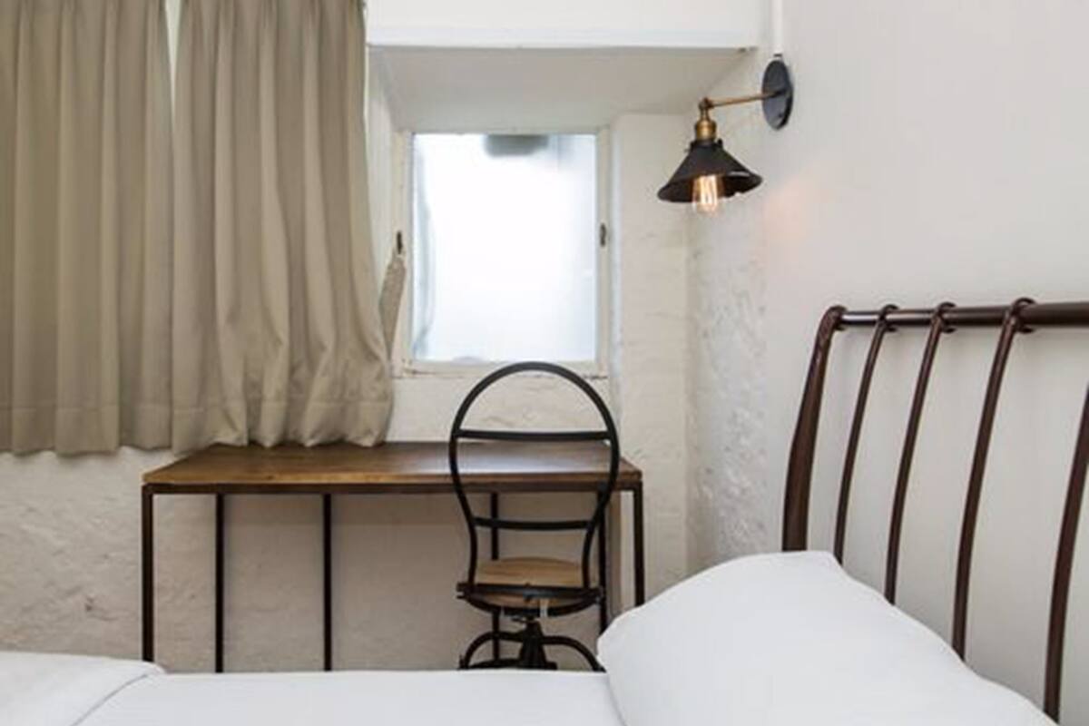 A bedroom with a bed, a desk, and a chair.