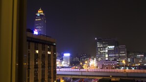 Panorama notturno di una città con edifici illuminati e un ponte.