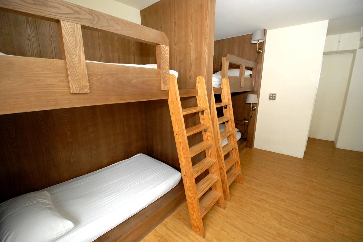 A bunk bed room with wooden headboards and a ladder.