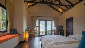 A bedroom with two beds, a desk, and a view of the sea. - Bintan SpaVilla Beach Resort (Bintan)