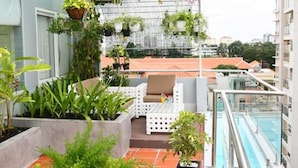 Una terraza en la azotea con piscina, plantas en macetas y mobiliario exterior.