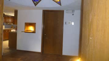 A hallway with a wooden door, a small window with a light, and a tiled floor.