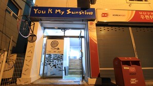 En butik med et skilt, der siger "You R My Sunshine", og en tydelig indgang.