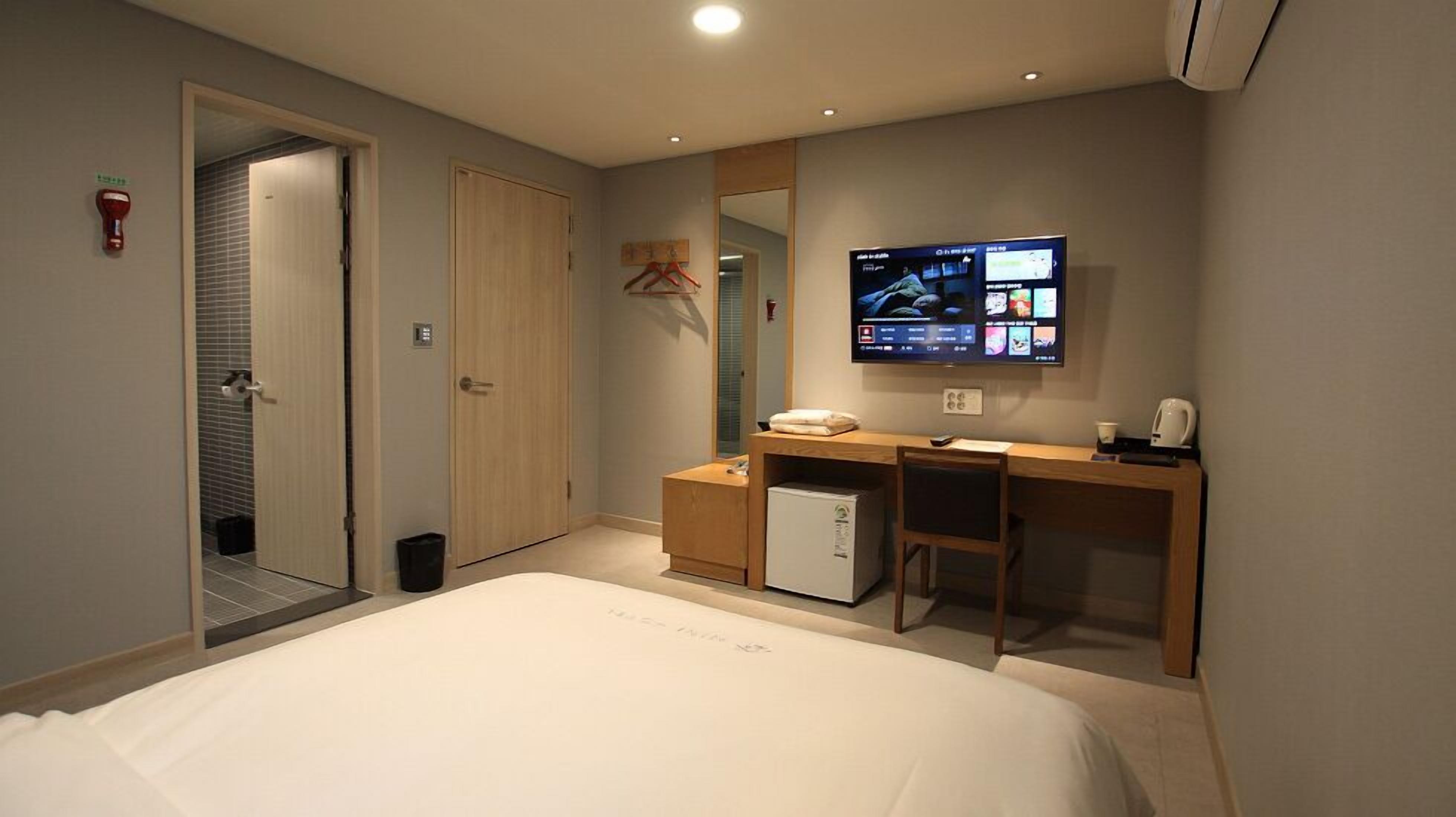 Habitació d'hotel amb un llit, escriptori, televisió i nevera petita.