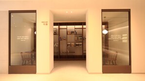 Un intérieur moderne avec une bibliothèque centrale, deux portes vitrées et un luminaire au plafond.