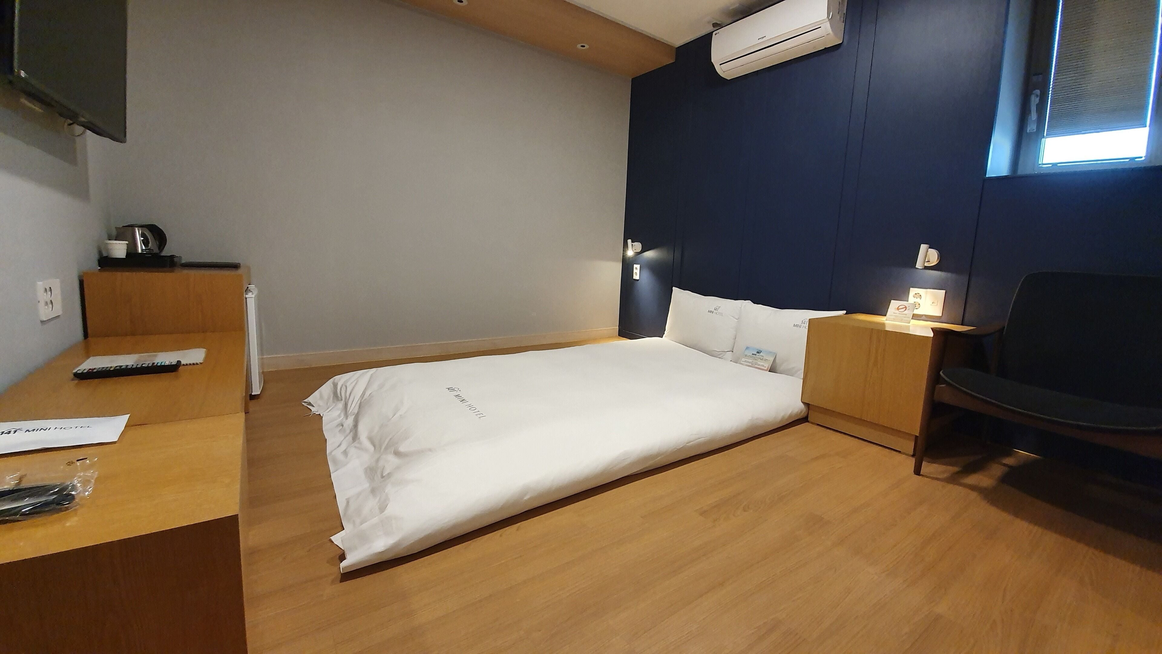 A hotel room with a bed, a desk, a chair, and a window.