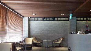 Un hall d’hôtel moderne doté de deux espaces salon, d’un comptoir d’accueil et d’une enseigne indiquant le « Gyeongju Korea Mini Hotel ».