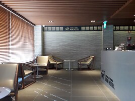 Moderni hotellin aula, jossa on kaksi oleskelualuetta, vastaanottotiski ja kyltti, jossa lukee Gyeongju Korea Mini Hotel.