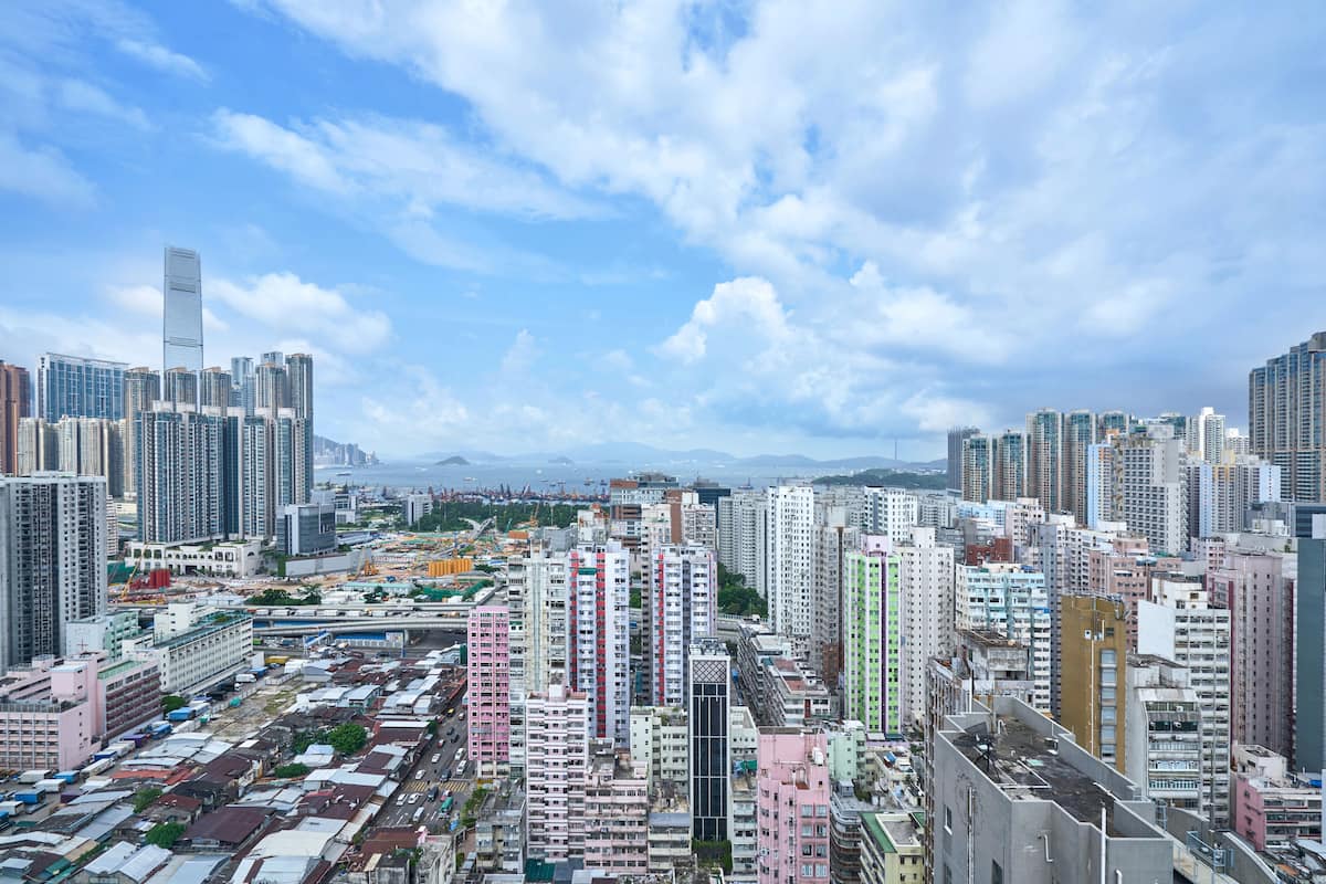 A high-rise urban area with dense residential and commercial buildings, a clear sky, and distant mountains.