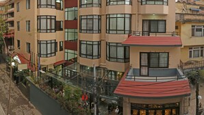 A multi-story hotel with a central courtyard, balconies, and a mix of window styles. - Fuji Hotel (Kathmandu)