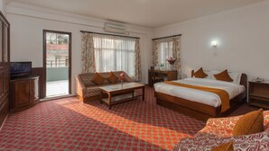 A hotel room with a bed, a sofa, a television, a desk, and a window with curtains. - Fuji Hotel (Kathmandu)