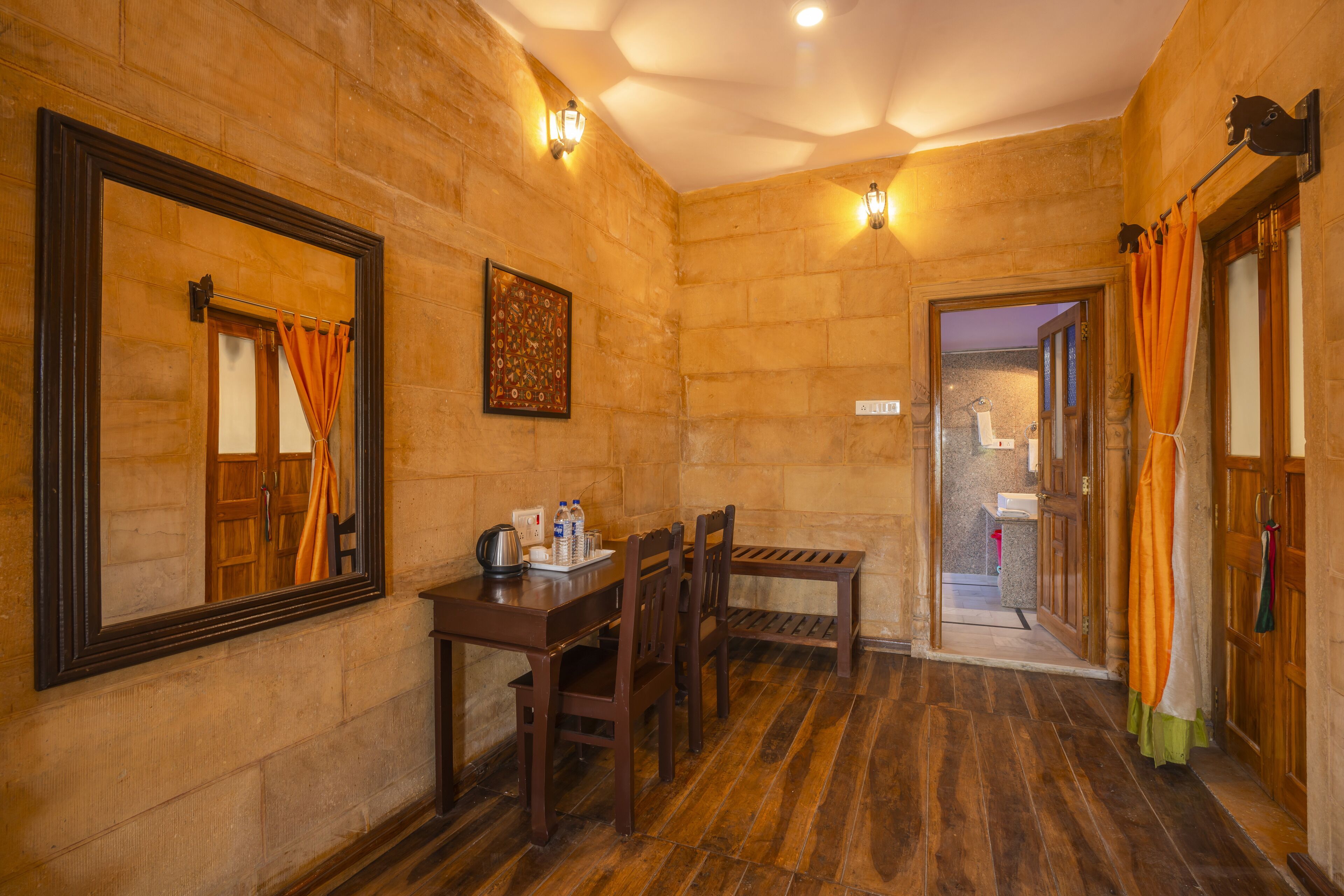 Una habitación con piso de madera, una mesa de madera con sillas, un espejo grande y un cuadro en la pared.
