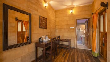 Una habitación con piso de madera, una mesa de madera con sillas, un espejo grande y un cuadro en la pared.