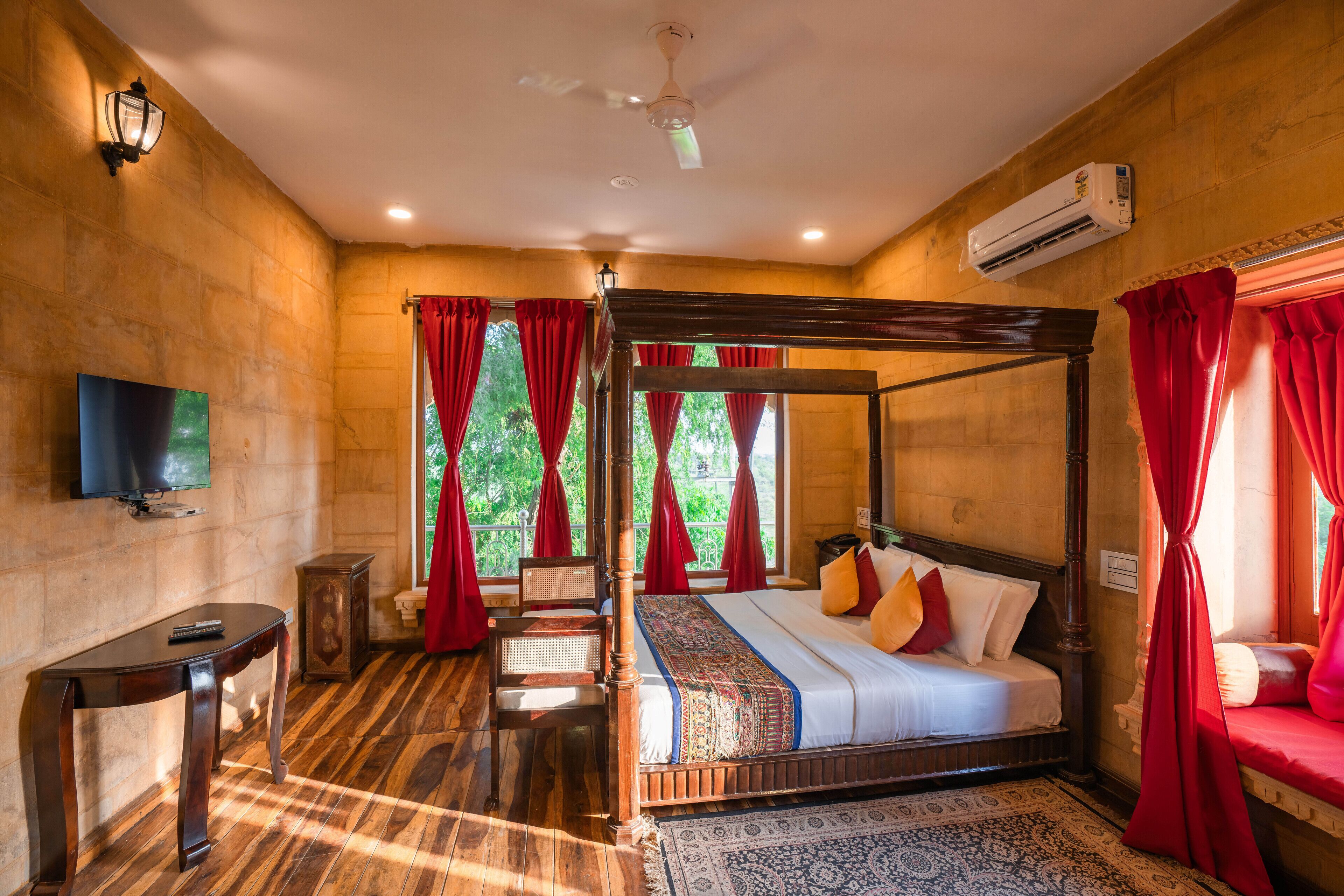 A four-poster bed with a canopy, a television on the wall, and a wooden floor.