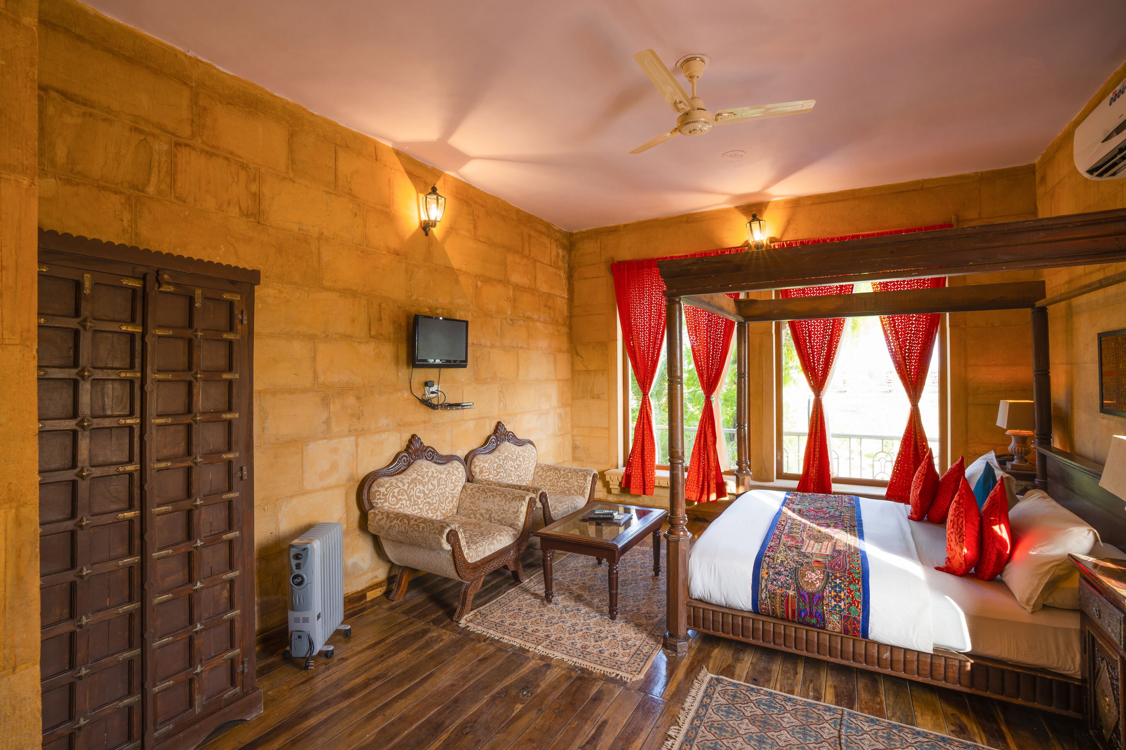A traditional room with a wooden bed, two upholstered chairs, a small table, and a television.