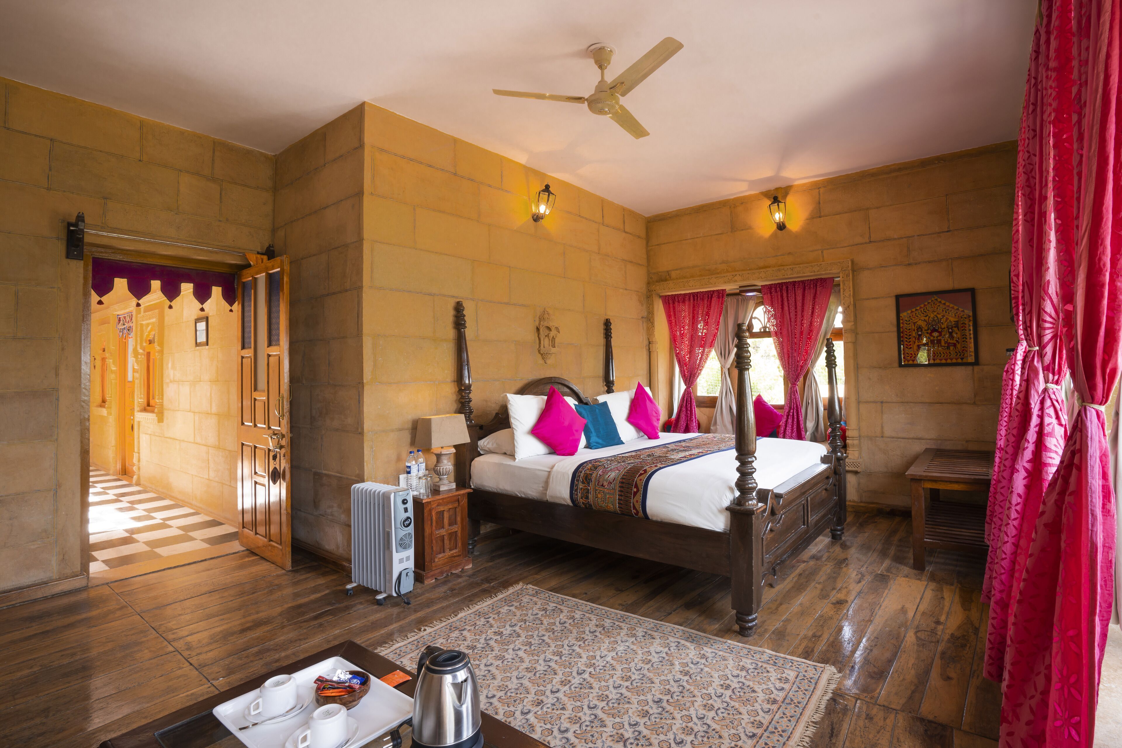 A spacious bedroom with a large bed, a ceiling fan, a radiator, and a wooden floor.