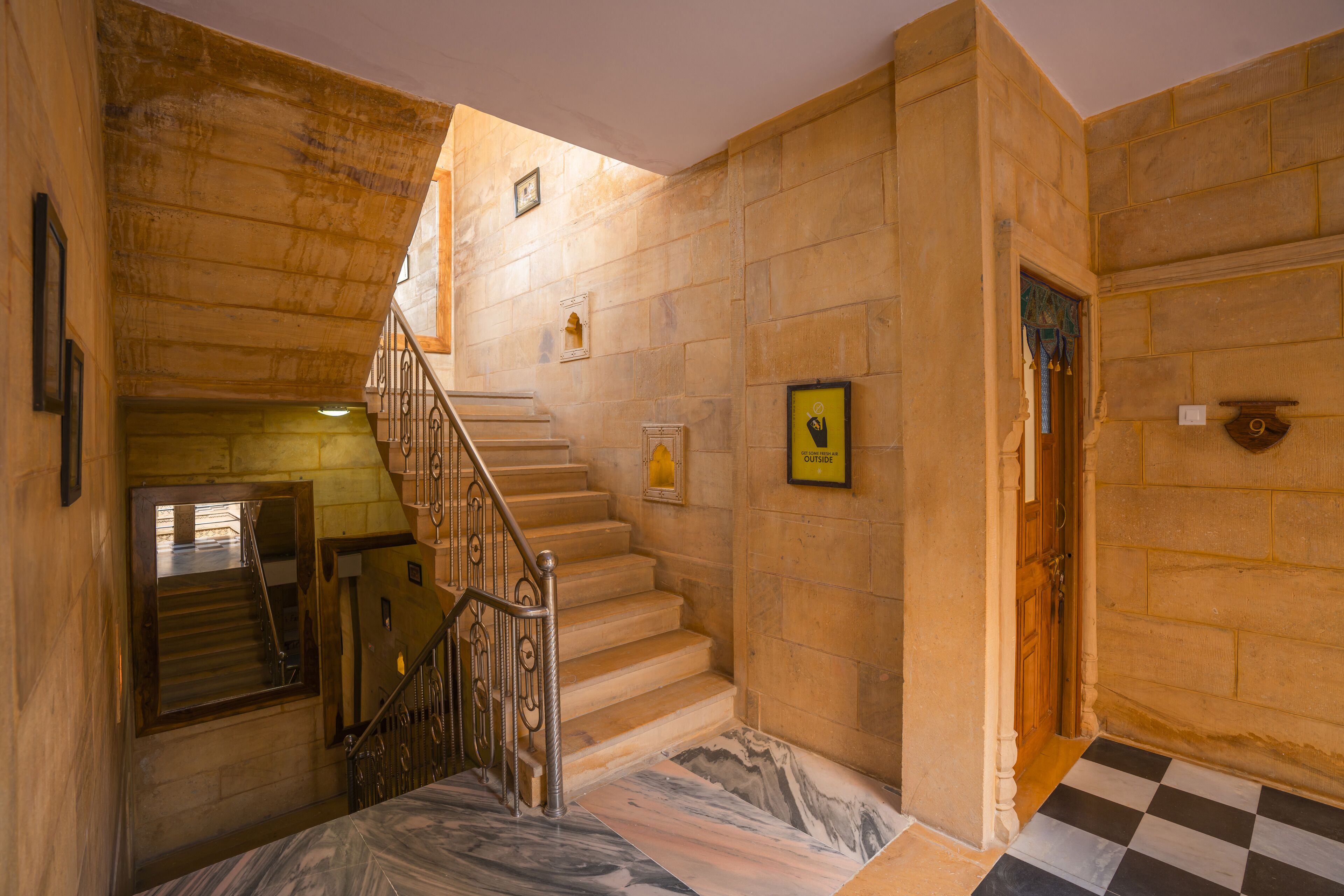 A staircase with marble steps, a wooden door, and a checkered floor.