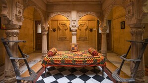 Una habitación con suelo a cuadros, una cama con colcha colorida y detalles arquitectónicos ornamentados.