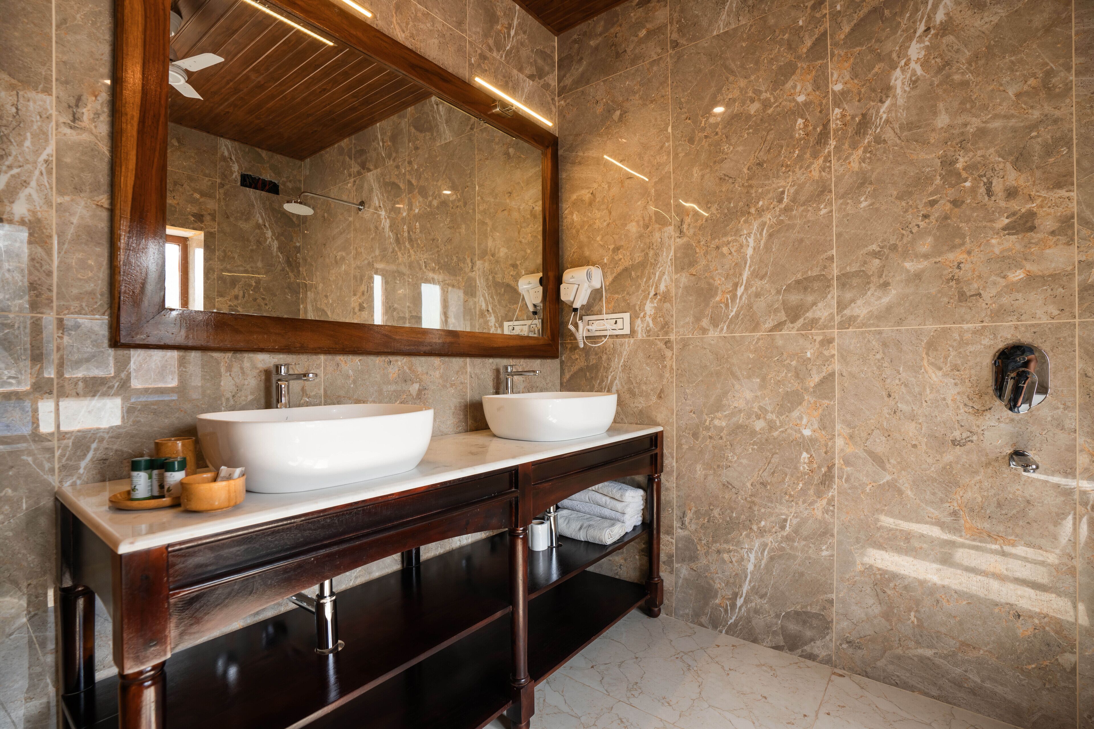 A bathroom with two sinks, a large mirror, and marble walls.