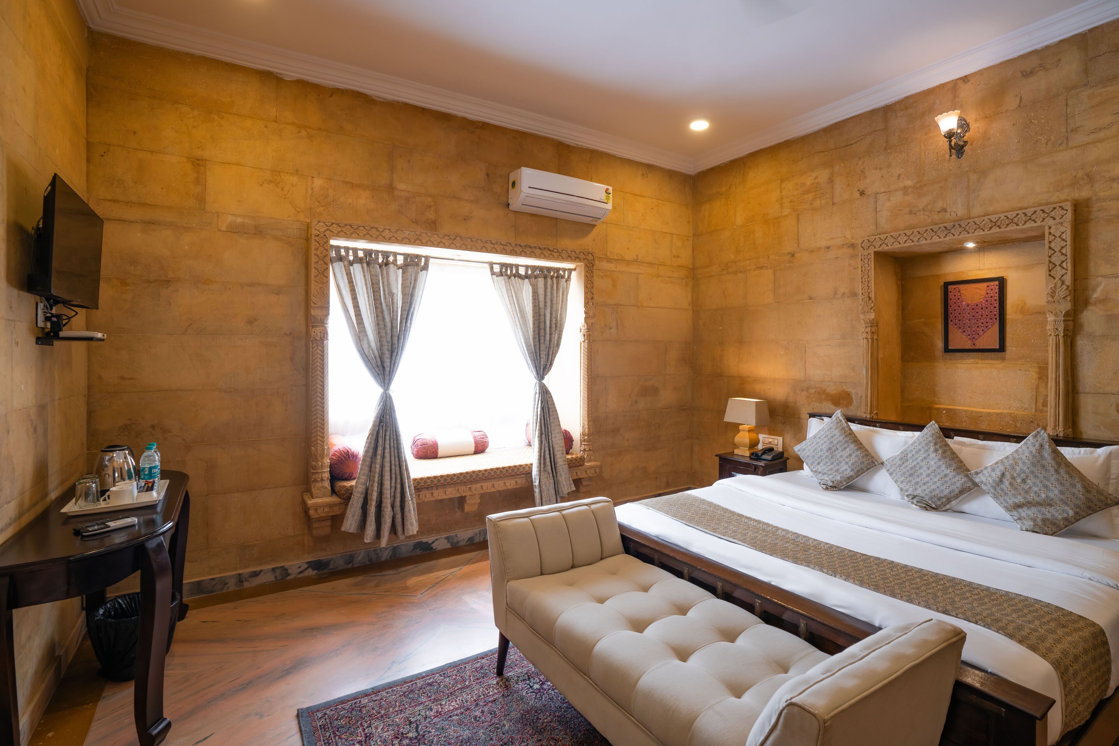 Una habitación de hotel con una cama grande, un sofá, un televisor y una ventana con cortinas.